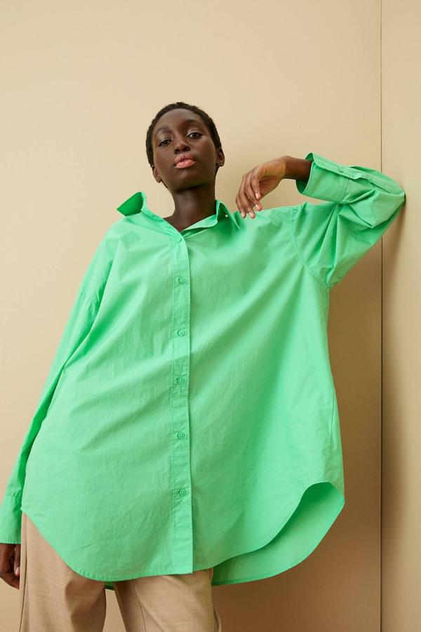 Camisa oversize de algodón con cuello clásico, cierre de botones, pliegues en la espalda y bajo redondeado, color verde claro, de H&M. La encontrarás por 19,99 euros.