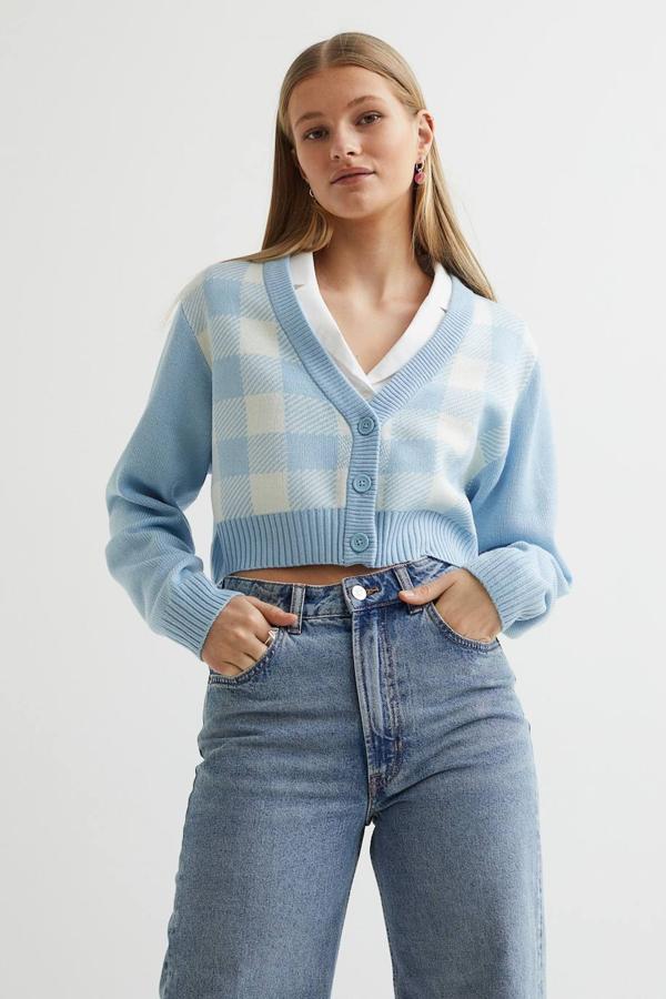 Cárdigan corto de punto suave con diseño de cuadros, escote de pico, cierre de botones y acabados en rib, en azul claro y blanco, de H&M. Cuesta 14,99 euros y está disponible en otros 5 colores y estampados.