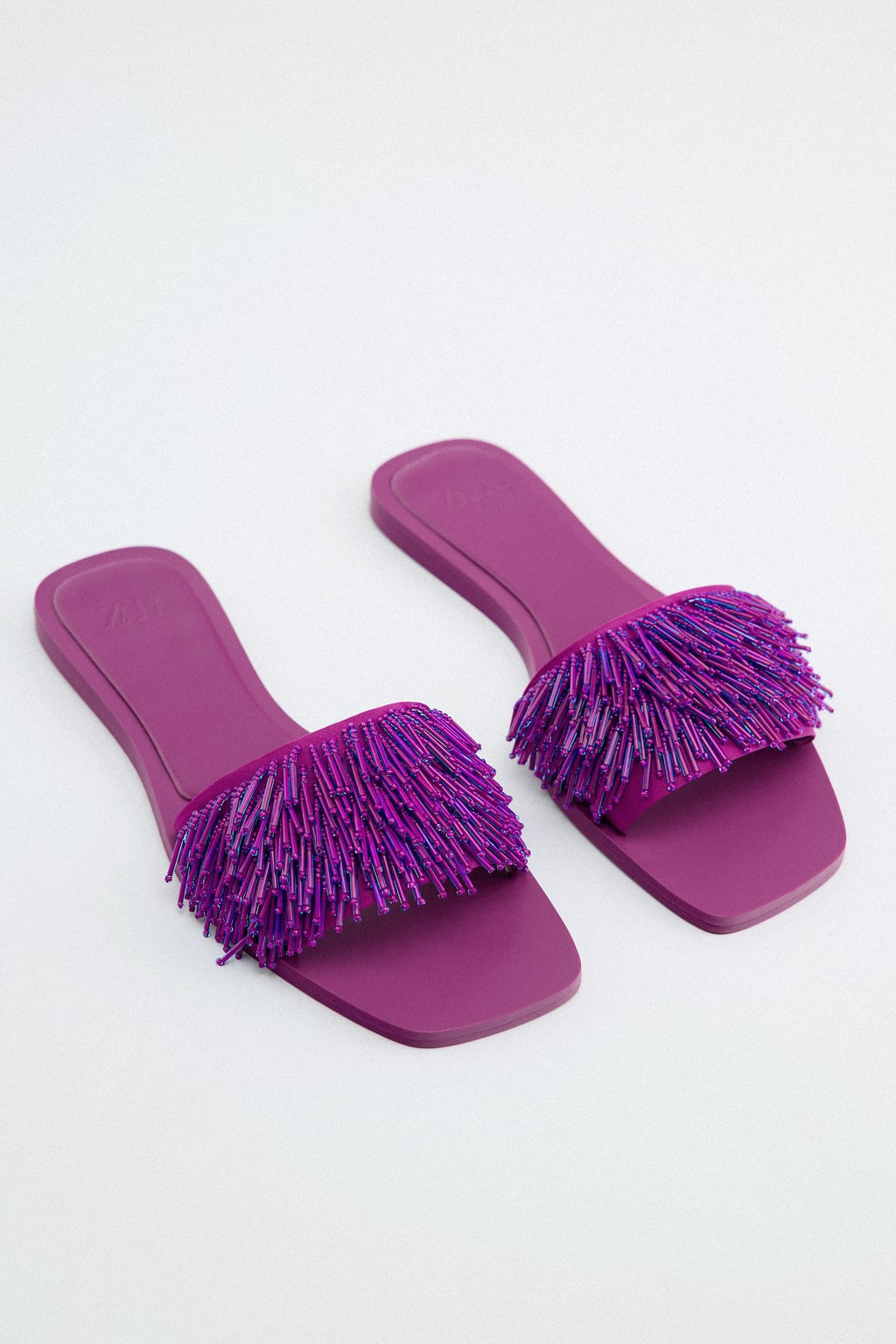 Aunque parece que ya está todo inventado, siempre hay diseños nuevos que sorprenden. Como estas sandalias joya en color morado. Una propuesta especial que podrás llevar incluso con looks de noche. Sandalias planas de Zara (45,99 euros. 