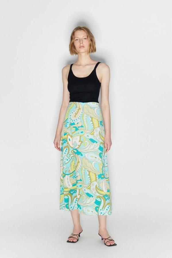 Falda midi confeccionada en tejido elástico con talle alto, diseño holgado con vuelo y print retro en tonos verdes, blanco y marrón. La encontrarás de las tallas S a la XL por 15,99 euros.