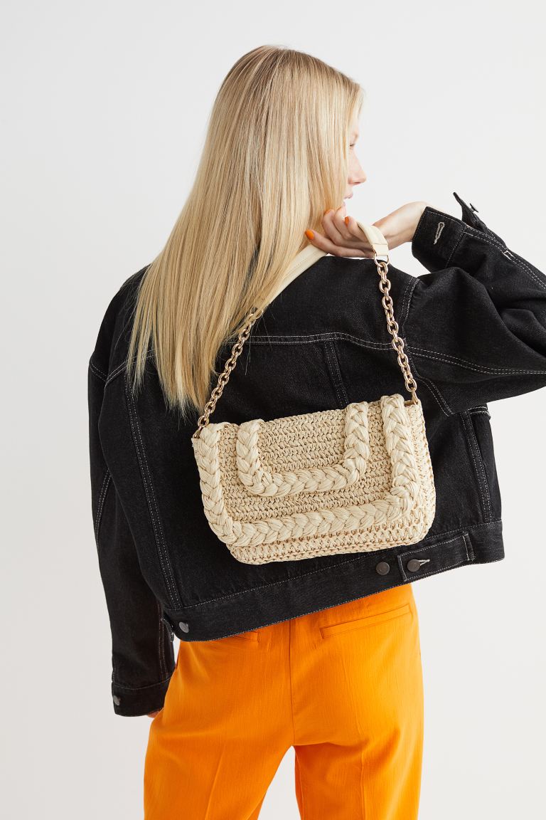 Los bolsos de rafia, en tamaño mini, son perfectos para rematar los planes más informales. Podrás llevarlos en la mano o recurrir a la comodidad de la cadena. Bolso trenzado de H&M (29,99 euros)