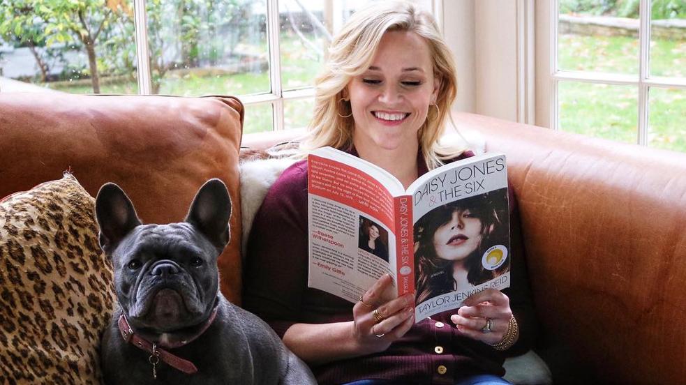 Reese Witherspoon leyendo Todos quieren a Daisy Jones, un libro que se convertirá en serie con ella a cargo de la producción. 