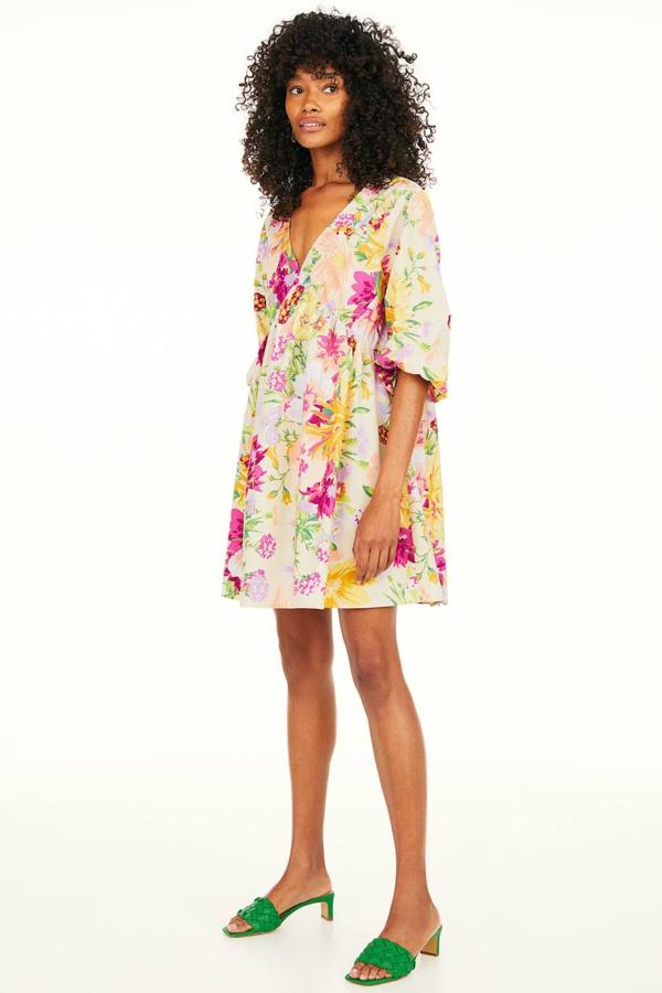 Vestido corto de algodón con silueta amplia, manga tres cuartos con volumen terminada en elástico, corte en el busto y escote de pico frontal y posterior, en floral print multicolor. Lo encontrarás por 19,99 euros.