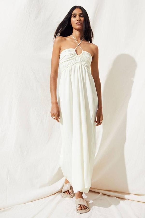 Vestido midi de tejido ligero con volumen, diseño sin mangas, tiras finas para anudas en el cuello, detalles fruncidos, busto entallado y falda con vuelo. Está disponible en crema, beige y negro, por 34,99 euros.