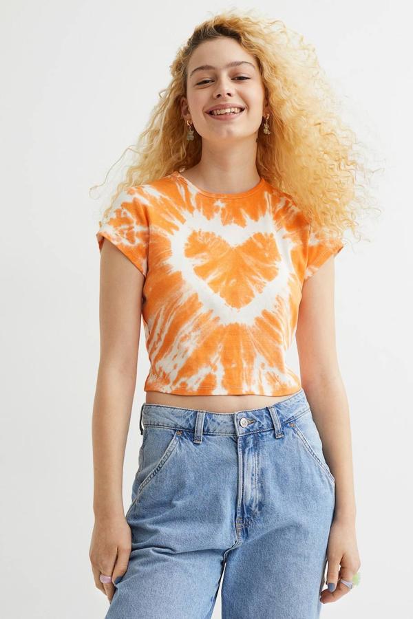 Camiseta cropped de manga corta con estampado tie dye en forma de corazón, color naranja y blanco, de H&M. Su precio es de 12,99 euros.