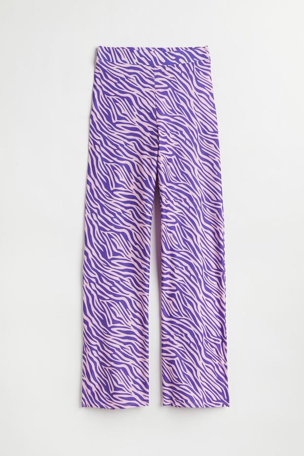En punto elástico con estampado de cebra en tonos lilas y morados, así es el pantalón tan original de H&M. Destaca sobre todo por sus aberturas en los bajos. Precio: 24,99 €.