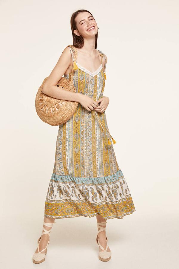 Vestido midi en tejido fluido con corte relajado y amplio, tirantes finos ajustables rematados con borlas a tono, escote en v con detalle de crochet, goma con cordones en la cintura y bajo acabado en volante, con estampado de cenefas tipo paisley color dorado. Está rebajado a  27,99 euros .