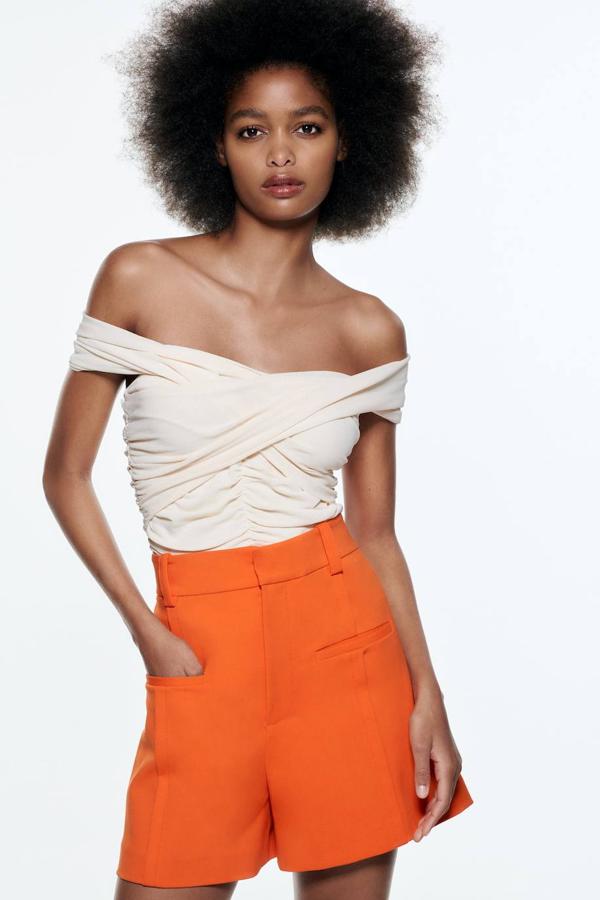 Bermudas de tiro alto con pernera ancha, trabillas para el cinturón, pespuntes marcados y falsos bolsillos de ojal, color naranja, de Zara. Tienen un coste de 25,95 euros.