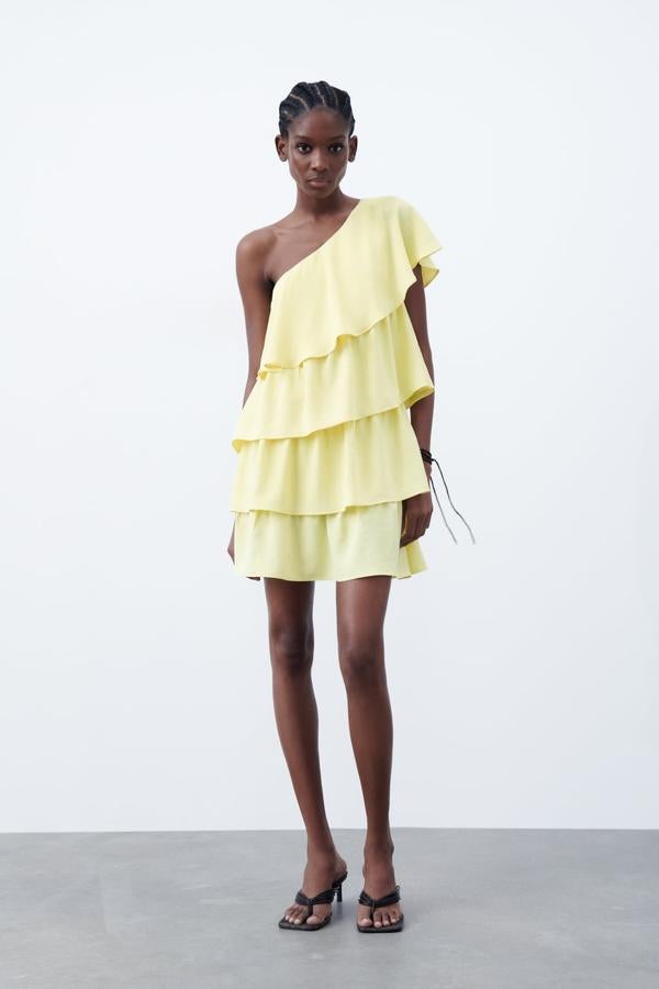 Los mini vestidos son otro de los mejores acompañantes veraniegos de los volantes. Este diseño asimétrico en color amarillo es la opción perfecta para lucir bronceado. Mini vestido con volantes de Zara (29,99 euros)