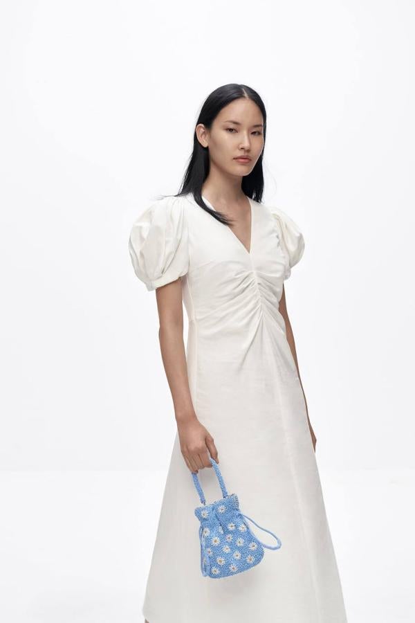Vestido blanco en tejido de lino con manga corta abullonada, cuello de pico, detalles fruncidos en el pecho y falda amplia con abajo acabado en evasé, de Zara. Cómpralo a 35,95 euros.