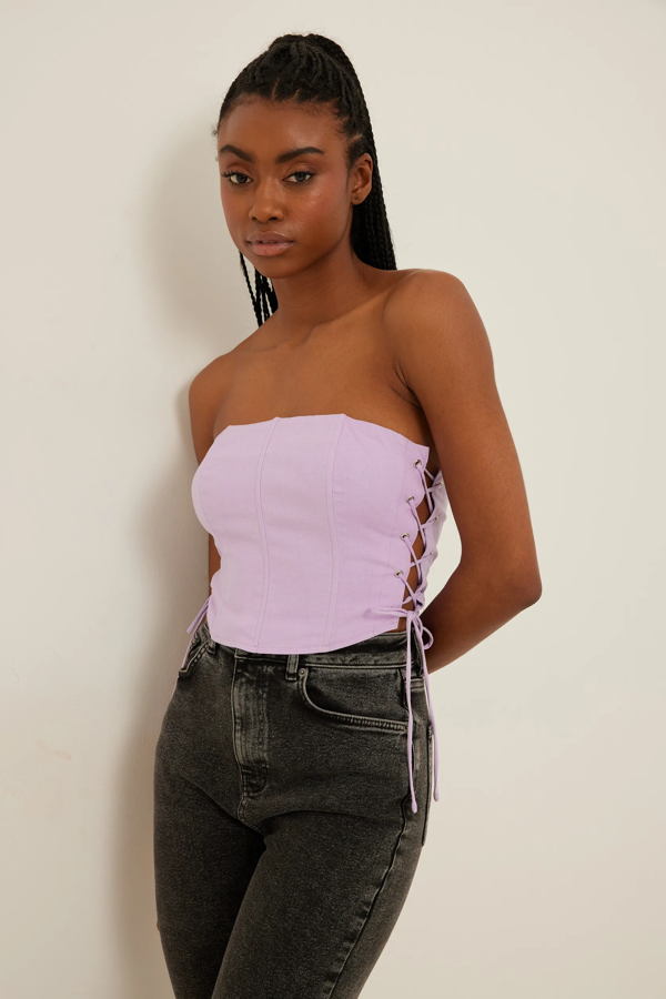 Con detalles de encaje en los laterales y con cierres de lazada. Así es el top estilo corsé que confecciona NA-KD. Precio: 43,95 €.