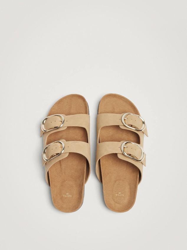 Sandalia plana con tiras anchas en material efecto piel suave, hebillas metálicas y suela de corcho, en beige. La encontrarás por 22,99 euros.