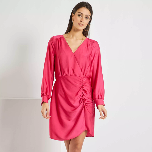 Vestido fucsia corto satinado. Destaca por su cuello cruzado de pico y por ser de manga larga.. Es de Kiabi Precio rebajado: 15 €. 