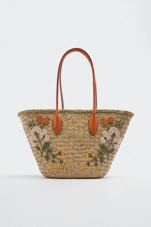 Capazo en tejido de rafia con detalles bordados de motivos florales y asas efecto piel, de Zara. Puedes comprarlo rebajado por 19,99 euros.