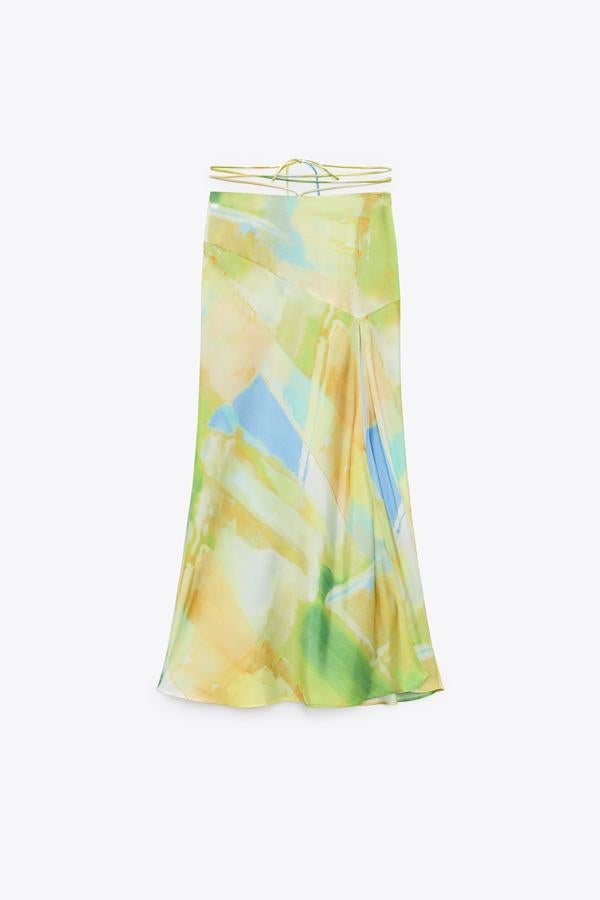 De estilo midi y tiro alto, posee interesantes cintas anudadas en la cintura. Destacar también el bajo con abertura frontal y su cierre lateral con cremallera oculta en costura, además del estampado satinado. Precio: 29,95 €.