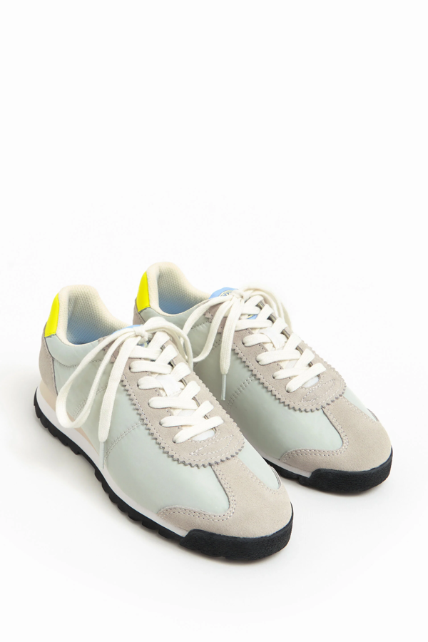 Zapatillas en color gris claro con modelo tipo running de inspiración retro con piezas de serraje combinadas con nylon. La parte trasera tiene una pieza en color amarillo y el logo está grabado a contraste, además de una llamativa suela tricolor. De Bimba y Lola. Precio rebajado: 63 €.