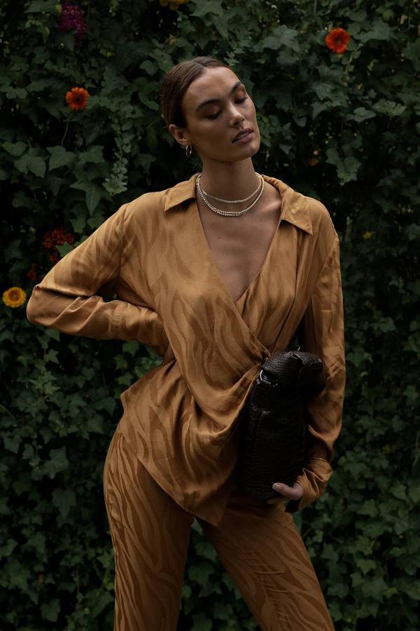 Total look jacquard en estampado de cebra color marrón, compuesto por camisa de cierre cruzado y pantalón largo fluido, de NA-KD. Las prendas cuestan rebajadas, 31,97 euros y 41,97 euros, respectivamente. Cómpralo aquí