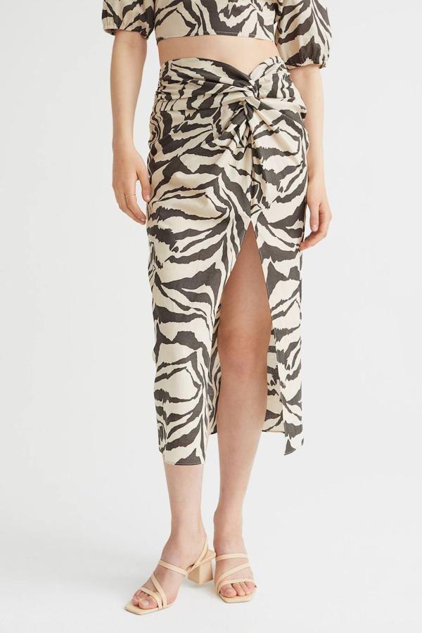 Falda midi drapeada de talle alto con abertura frontal en el bajo y animal print, de H&M. Tiene un precio de 29,99 euros.