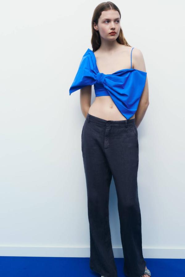 Top corto de tirantes finos con detalle de maxi lazada en la parte delantera, en tono azulón. Tiene un coste de 22,95 euros.