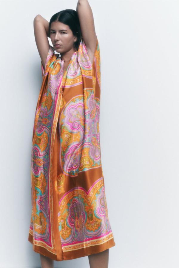 La versión más sofisticada del caftán llega con un estampado tipo pañuelo en tonos mostaza. Vestido satinado de corte midi de Zara (49,99 euros). 