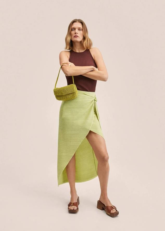 Falda midi en tejido de punto texturizado, tipo pareo, con diseño cruzado y detalle de nudo en la cintura, color verde lima, de Mango. Cuesta 27,99 euros.