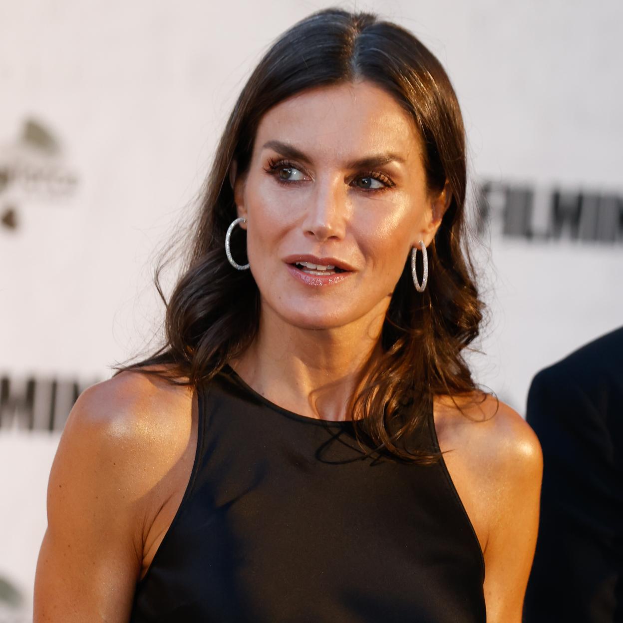 El vestido negro con brillo satinado de inspiración lencera de la reina Letizia es de & Other Stories y tiene un espectacular escote tipo nadadora.