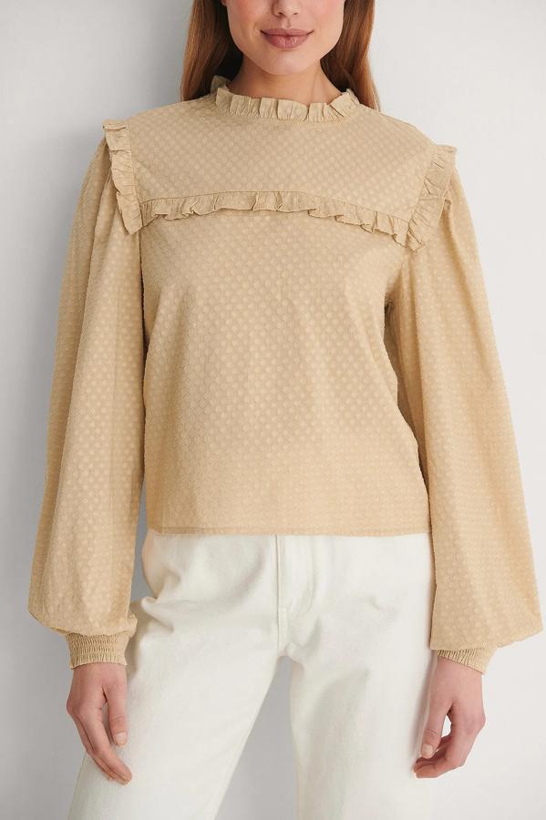 Blusa de cuello alto con detalles de volantes. Confeccionada con un cierre de cerradura detrás del cuello con botón y mangas largas con puños elásticos. Es de NA-KD. Precio: 38,95 €.