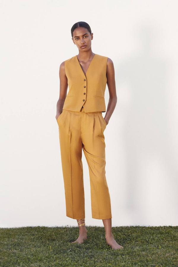 Traje en tono curry conformado por chaleco de diseño clásico con botones y pantalón tobillero con detalle de pinzas y cintura elástica, de Zara. Puedes comprar las piezas por 39,95 euros y 29,95 euros, respectivamente.