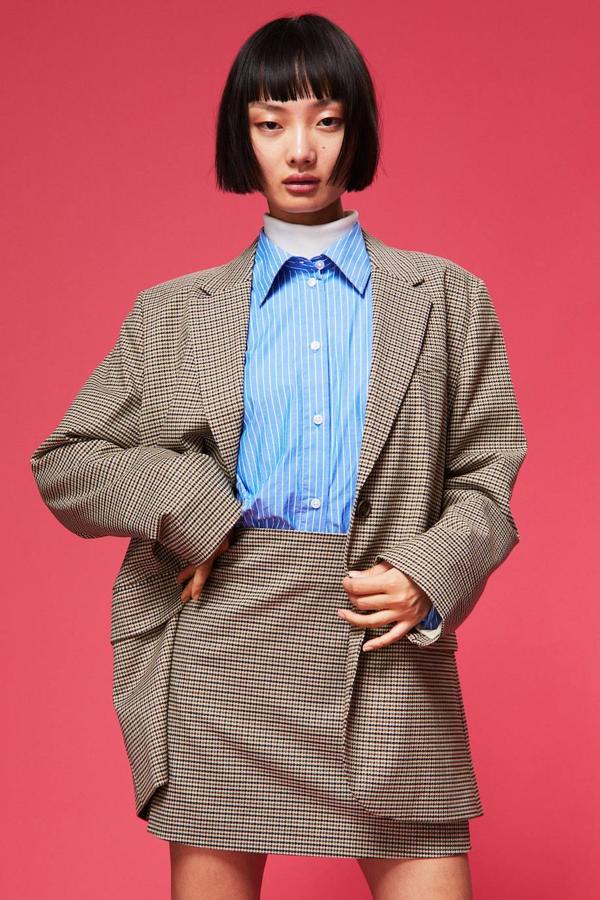 Conjunto de traje a cuadros en tono marrón con blazer oversize y mini falda. Las piezas están disponibles a 39,99 euros y 19,99 euros.