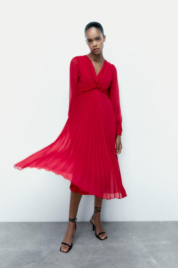 Vestido rojo de escote pico con nudo y manga larga acabada en puño con frunces. Su corte midi es ideal para lucirlos con cualquier tipo de complementos. Además, el rojo vibrante se puede combinar con joyas metalizadas para crear una sensación sofisticada. Es de Zara. Precio: 39,95 €.