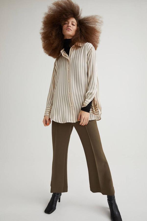 Camisa en tejido fluido luminoso, con corte relajado, cuello solapa, manga larga y cierre de botones, en estampado a rayas dobles beige claro y gris. Su coste es de 19,99 euros.