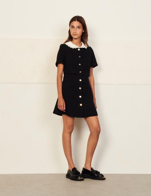 Vestido corto de tweed negro confeccionado en trampantojo. Diseñado con cuello tipo babero con bordados para crear contraste y botonadura dorada en la parte delantera. Es de Sandro Paris. Precio: 295 €.