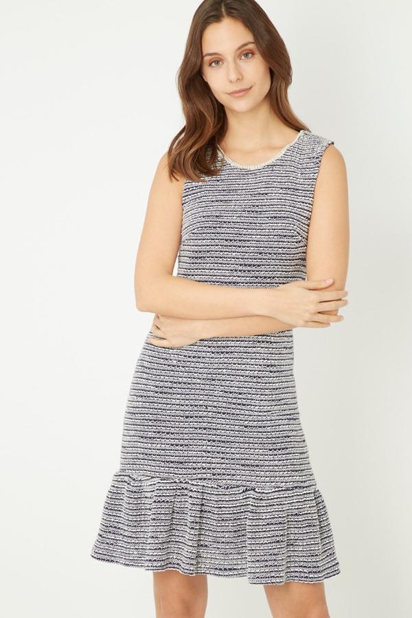 Vestido corto de tweed con escote redondo y tirantes finos. Diseñado con volantes en el bajo para crear un efecto fluido. Es de Tutto Tempo. Precio: 15 €.