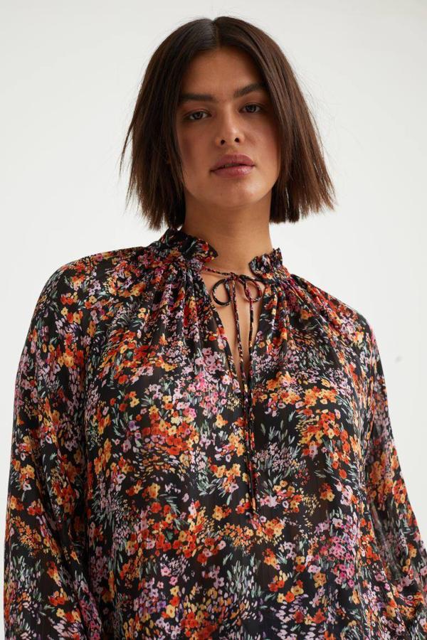 Seguimos con una blusa de tejido fluido que tiene un cuello con un volante y una abertura.