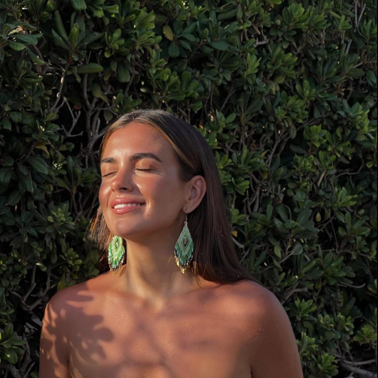 La influencer española Inma Cebreiro posando con un maquillaje ligero y unos pendientes verdes.