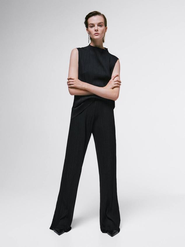 Conjunto en tejido plisado compuesto por top de cuello elevado y manga sisa, más pantalón largo y fluido, color negro, de Massimo Dutti. Las prendas cuestan 29,95 euros y 49,95 euros, respectivamente.