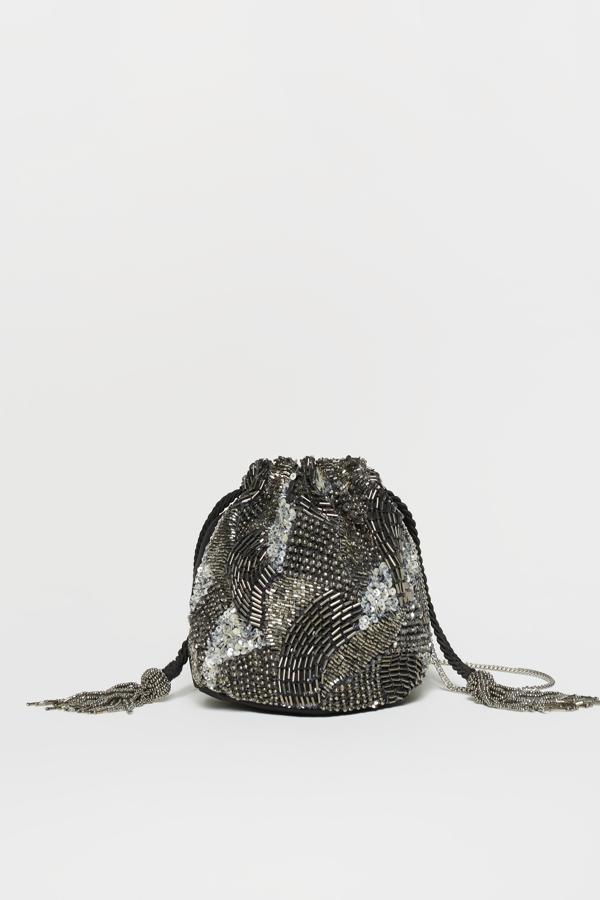 Bolso tipo saco con apliques de lentejuelas plateadas con detalles de borlas en la cadena. Es de Sfera. Precio: 15,99 €.