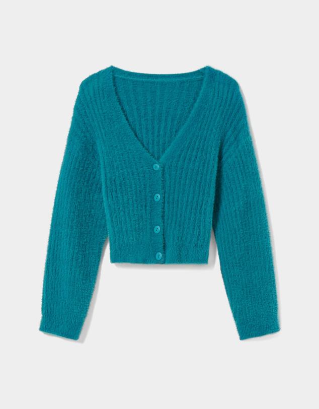 Cárdigan de cuello en V con botonadura del mismo color. Podrás encontrarla de diferentes colores: azul, blanco y naranja. Un básico para combinar con pantalones sastre o tus vaqueros más casuales. Es de Bershka. Precio: 22,99 €. 