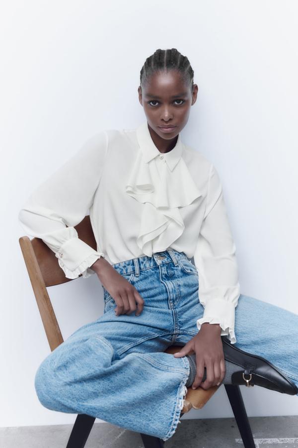 Una camisa blanca diferente, fluida y cubierta de volantes. Blusa blanca de Zara (25,99 euros). 