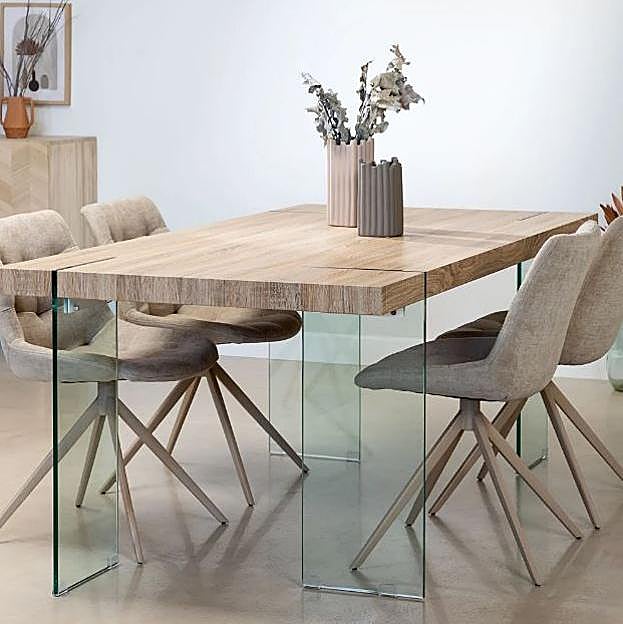 Una mesa de comedor con mucho carácter con patas de vidrio y estructura de madera.