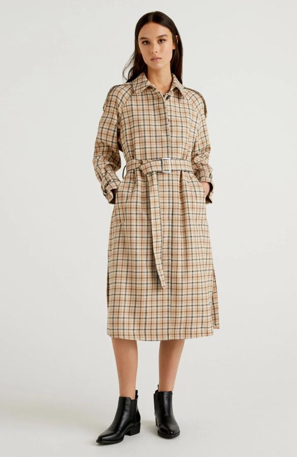 Gabardina con estampado de cuadros, botonadura frontal oculta, bolsillos en los laterales y abertura en la parte trasera. Detalles clásicos: manga raglán, cuello con gancho de metal, presillas en los puños, hombreras y cinturón con hebilla de metal. Precio: 94,50 euros en Benetton (precio habitual: 189 euros). Cómpralo aquí