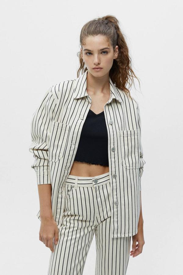 Sobrecamisa en tejido denim con silueta relajada, cuello solapa, manga larga, bolsillos de plastrón, cierre de botones y estampado a rayas en blanco y negro, de Pull&Bear. Su coste es de 29,99 euros.