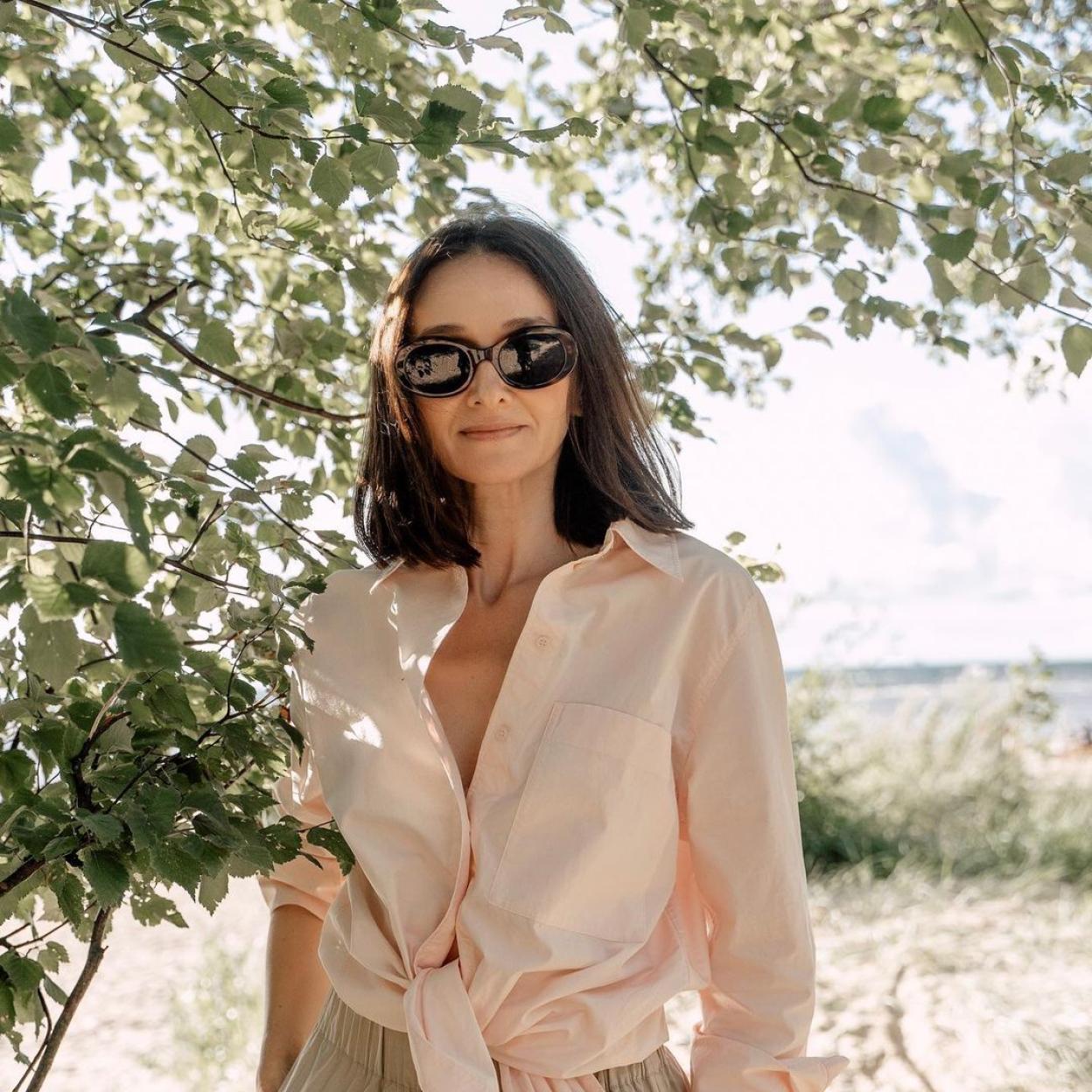 La influencer Masha Ohlezneva con una camisa de lino anudada y unas gafas de sol negras. 