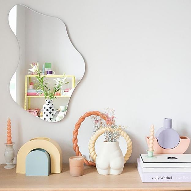 Un espejo de forma curiosa para dar movimiento al recibidor.