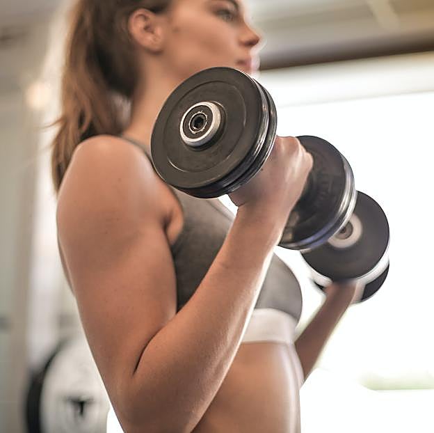 Mujer realizando ejercicios de brazos con mancuernas. 