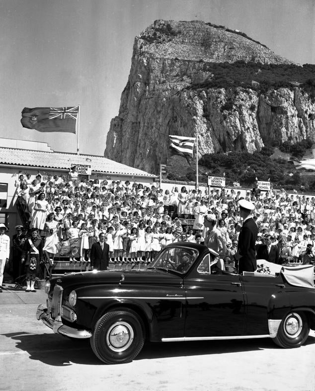 La reina y el Duque de Edimburgo son aclamados por niños que ondean banderas mientras recorren el estadio Victoria, al pie del Peñón de Gibraltar.