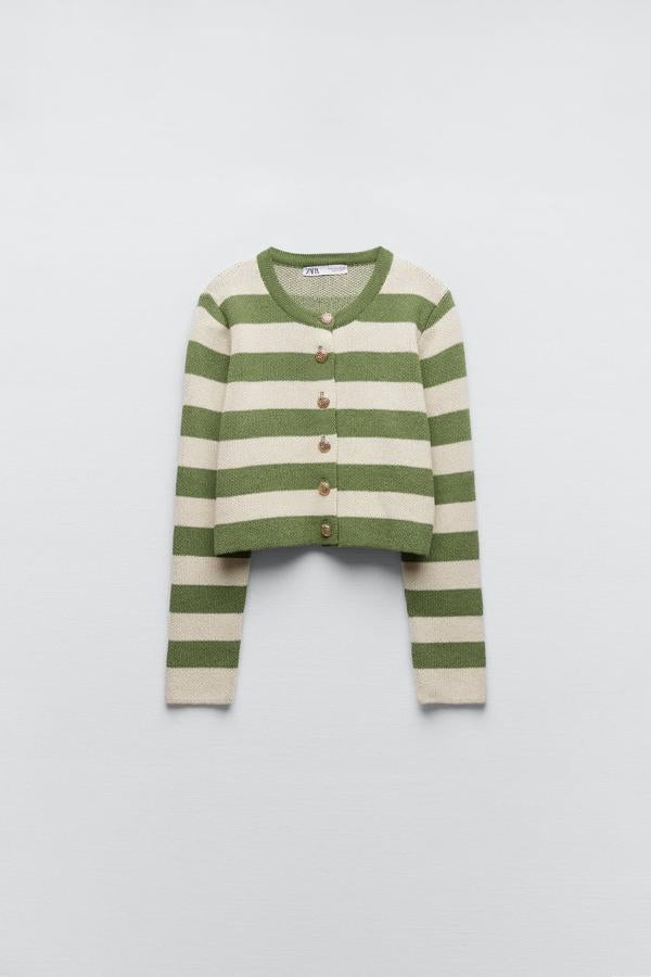 Una versión más reljada, en verde y crudo, de esta chaqueta con botones dorados. Cárdigan de punto con rayas de Zara (29,99 euros). 