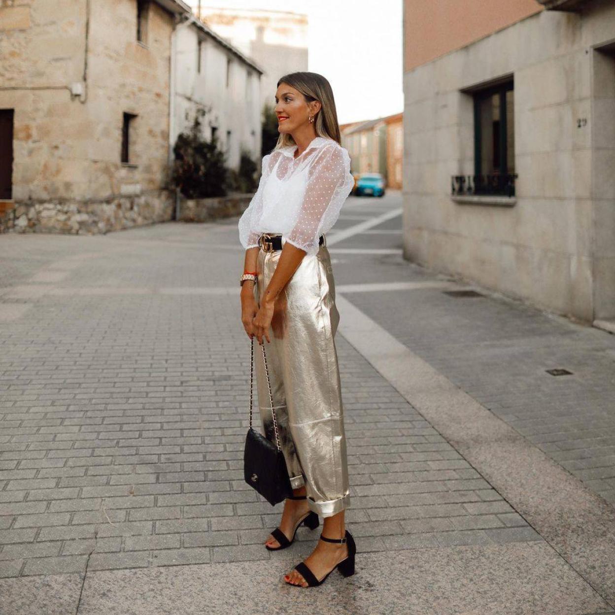 Influencer con pantalón metalizado dorado y blusa romántica de plumeti