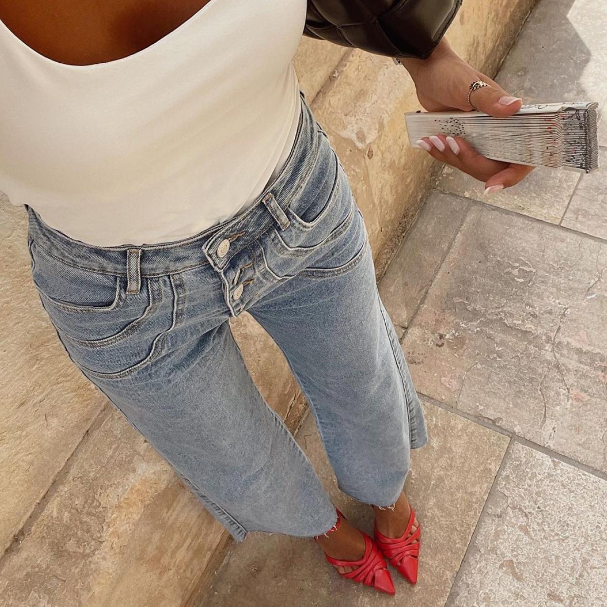 La influencer luce unas bailarinas rojas que combina con unos vaqueros azules y una camiseta sin mangas blanca. 