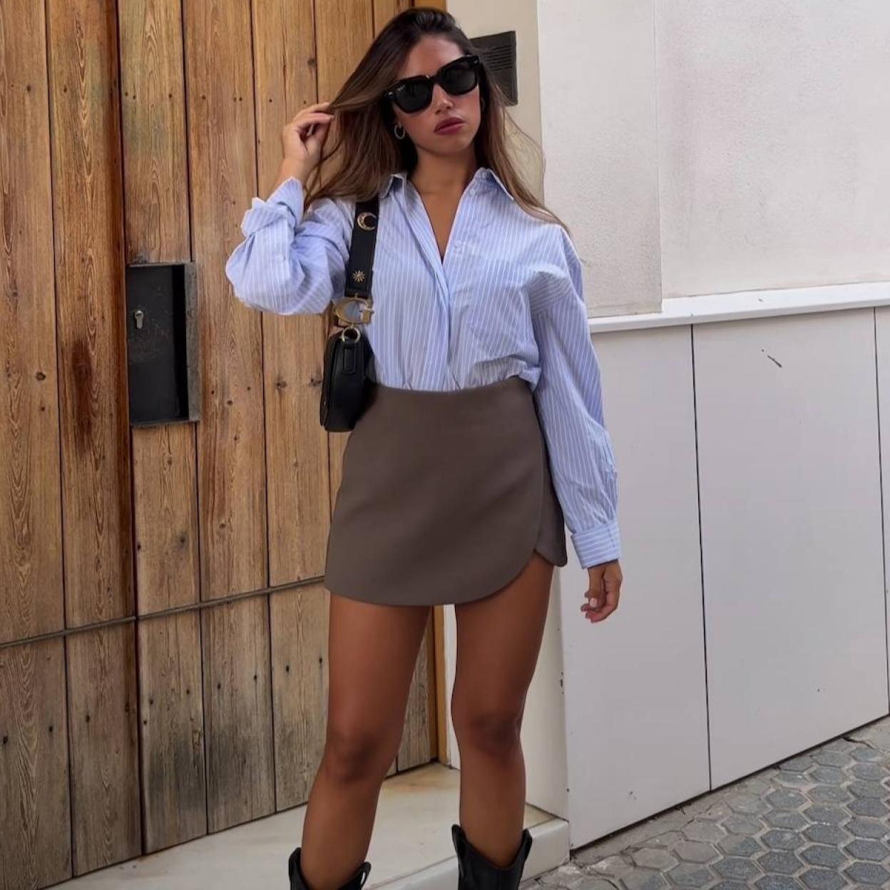 Influencer con look básico de camisa a rayas, falda pantalón y botas cowboy